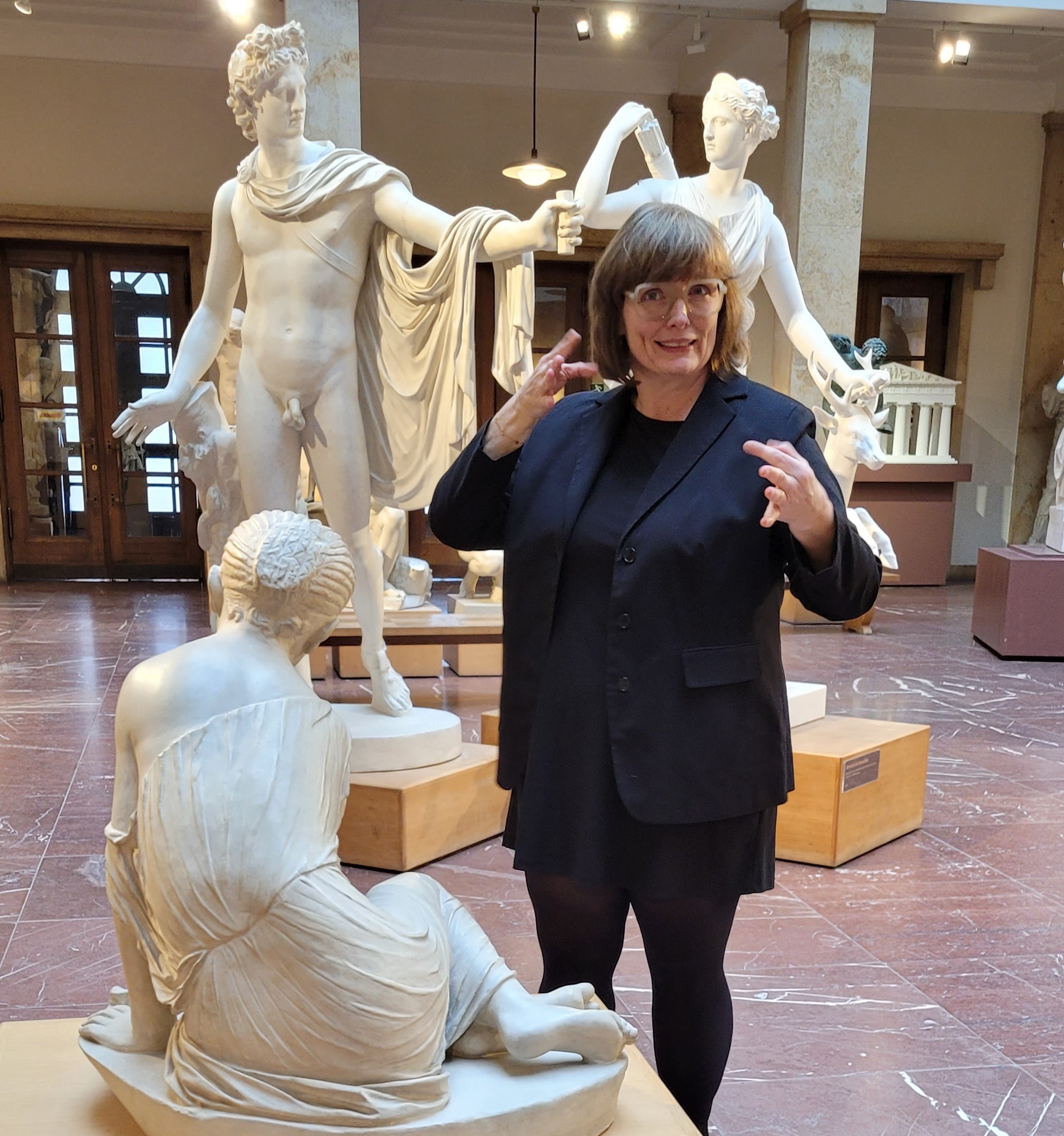 Eine Frau mittleren Alters gebärdet vor den Statuen im Museum