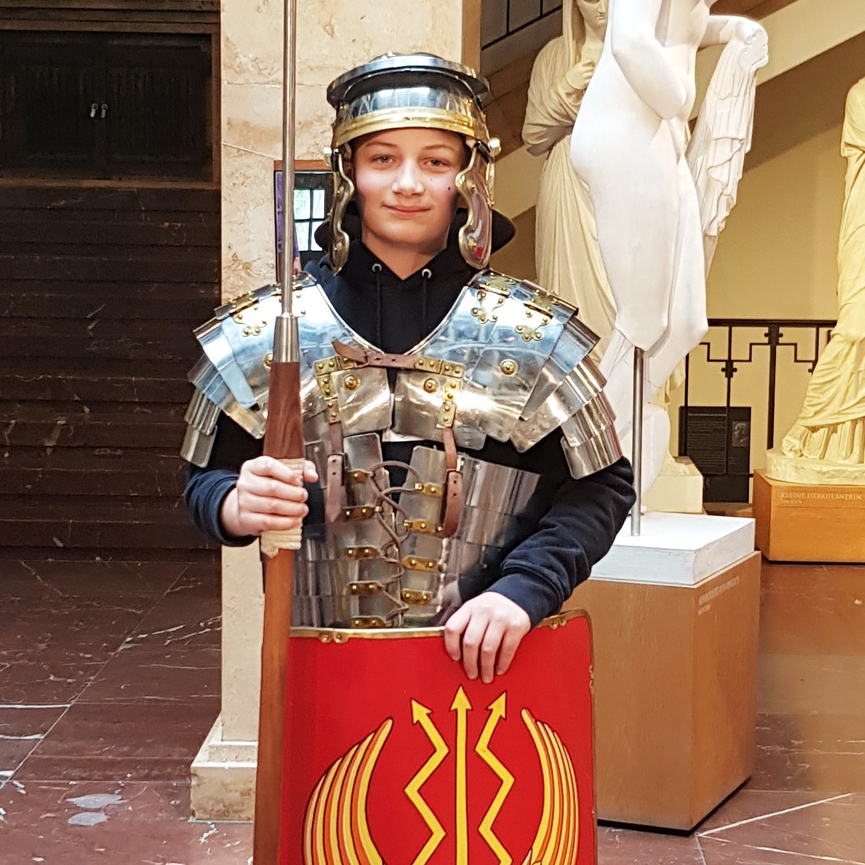 Ein Junge steht im Museum und ist als römischer Legionär verkleidet